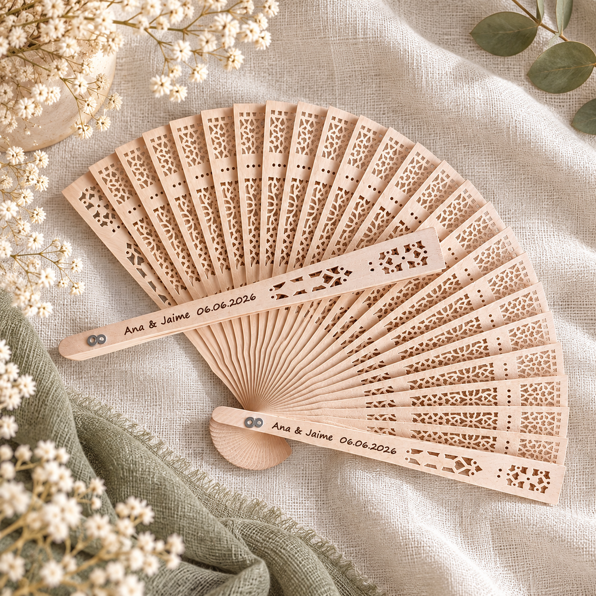 Abanico de madera personalizado con grabado láser de nombres y fecha de boda, sobre tela de lino con flores blancas secas